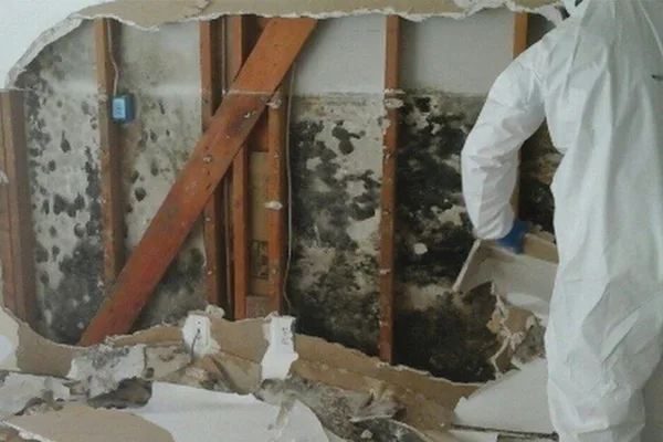 mould-rem A man in a white coat stands in a burned home, assessing the damage caused by the fire.